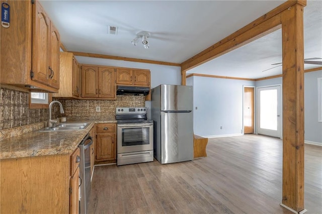 kitchen with light stone countertops, sink, stainless steel appliances, crown molding, and hardwood / wood-style flooring