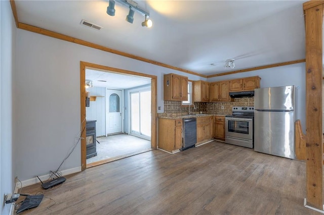 kitchen with decorative backsplash, appliances with stainless steel finishes, ornamental molding, and hardwood / wood-style floors