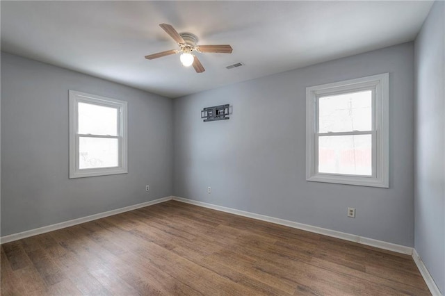 empty room with plenty of natural light, ceiling fan, and wood-type flooring