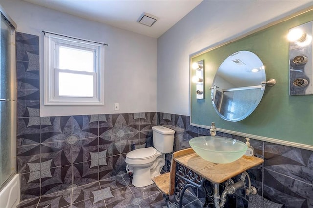 full bathroom featuring sink, tile walls, enclosed tub / shower combo, tile patterned flooring, and toilet