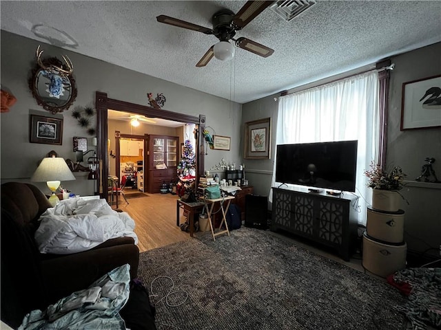 living room featuring ceiling fan, hardwood / wood-style floors, and a textured ceiling