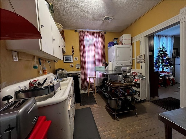 kitchen with white cabinetry, stacked washing maching and dryer, dark hardwood / wood-style floors, refrigerator, and a textured ceiling