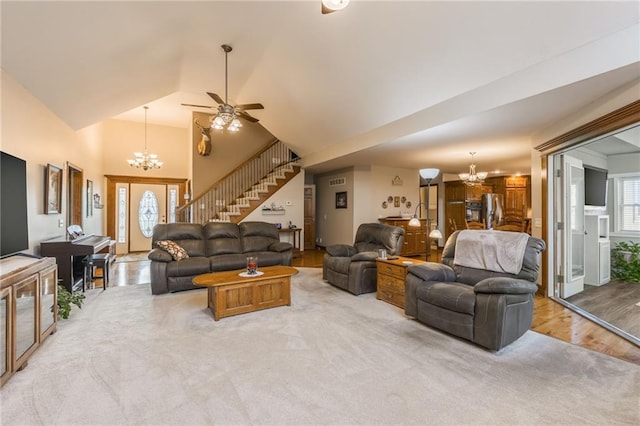 carpeted living room with ceiling fan with notable chandelier and vaulted ceiling