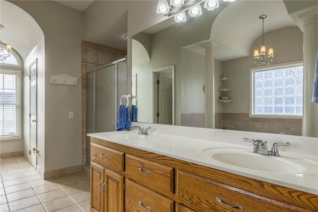 bathroom featuring tile patterned floors, ornate columns, vanity, a shower with door, and a chandelier