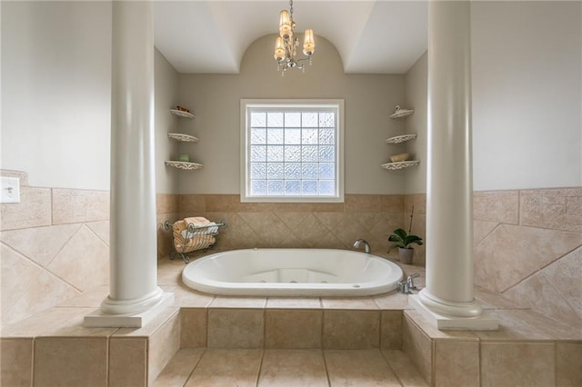 bathroom with a chandelier and tiled bath