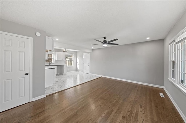 unfurnished living room with ceiling fan, sink, and hardwood / wood-style flooring