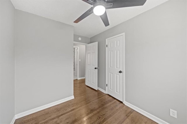 unfurnished bedroom featuring ceiling fan and dark wood-type flooring