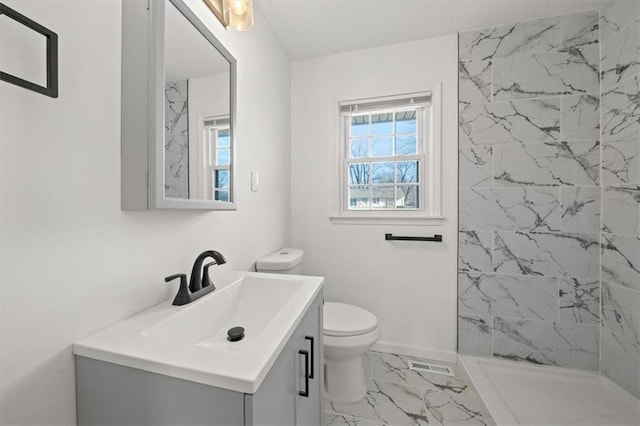 bathroom featuring toilet, vanity, and tiled shower