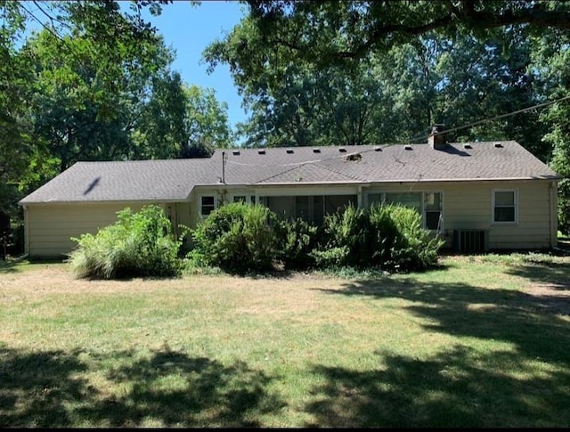 back of property with a yard and central AC