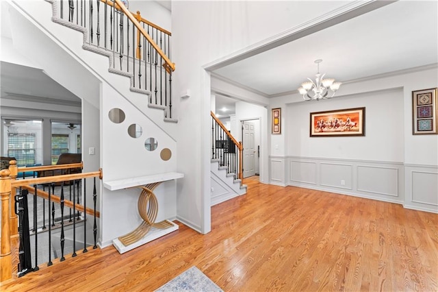 stairway featuring hardwood / wood-style flooring, crown molding, and an inviting chandelier