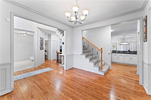 foyer entrance featuring a chandelier, light hardwood / wood-style flooring, and ornamental molding