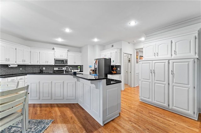 kitchen with decorative backsplash, light wood-type flooring, white cabinetry, and appliances with stainless steel finishes