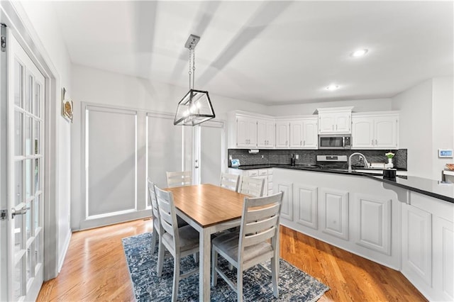 kitchen featuring stove, white cabinetry, hanging light fixtures, and light wood-type flooring