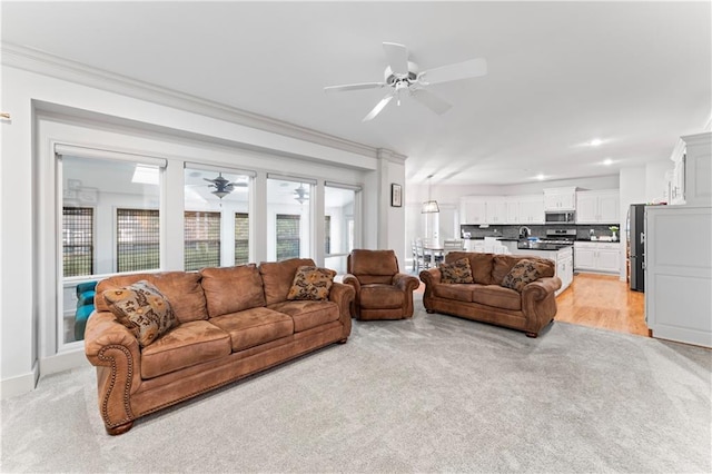 carpeted living room featuring ceiling fan and ornamental molding