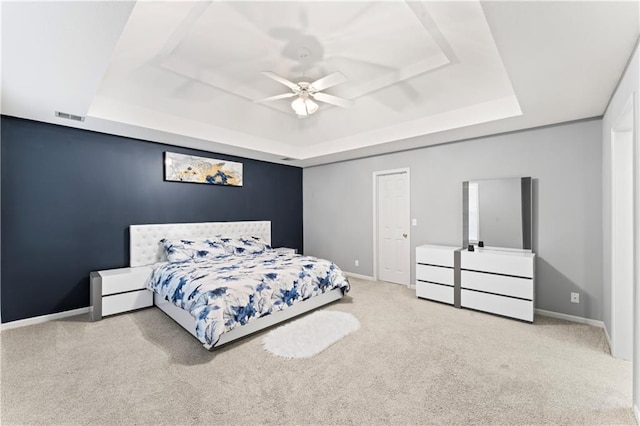 carpeted bedroom featuring ceiling fan and a raised ceiling