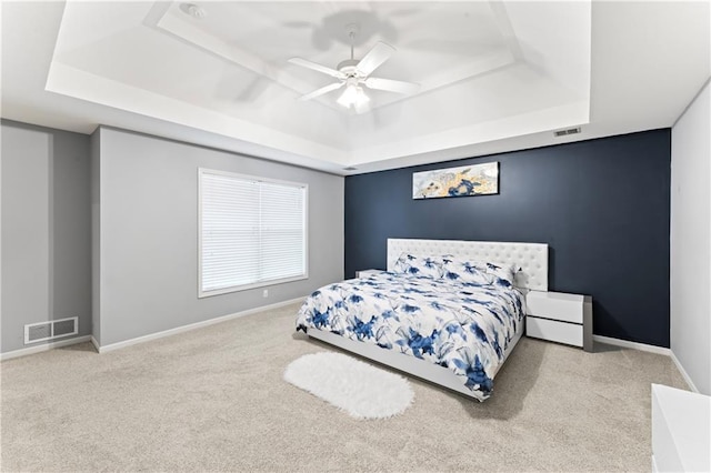 carpeted bedroom featuring ceiling fan and a tray ceiling