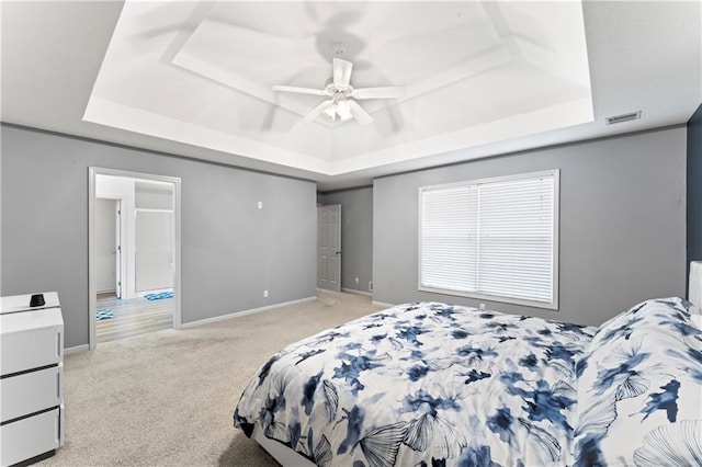 carpeted bedroom featuring ceiling fan and a raised ceiling