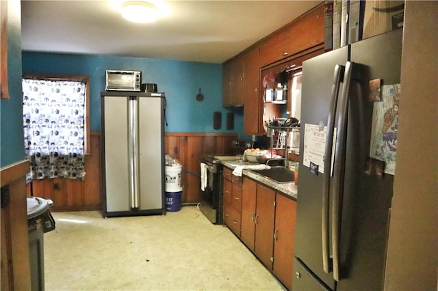 kitchen featuring stainless steel fridge, black electric range, and wooden walls