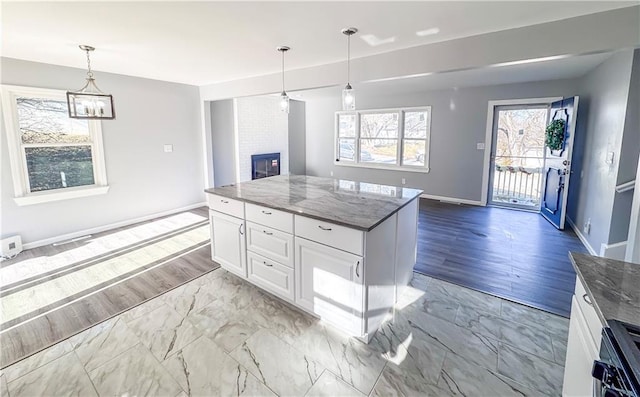 kitchen with wall oven, a fireplace, pendant lighting, dark stone countertops, and white cabinets