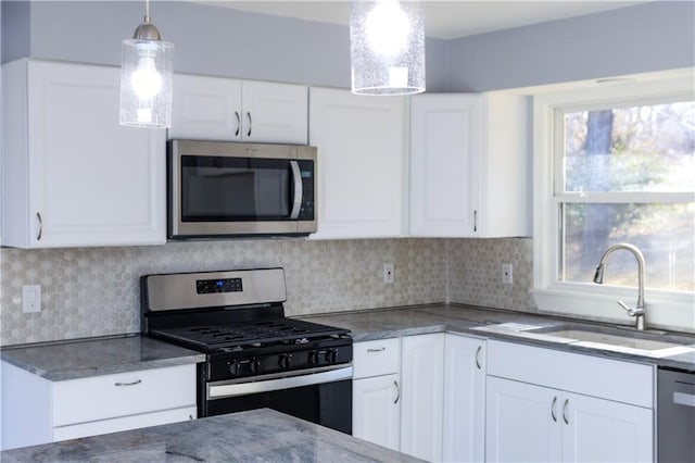 kitchen with white cabinets, stainless steel appliances, hanging light fixtures, and sink