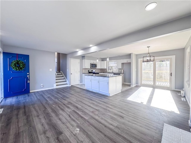 kitchen featuring appliances with stainless steel finishes, white cabinetry, hanging light fixtures, and a kitchen island