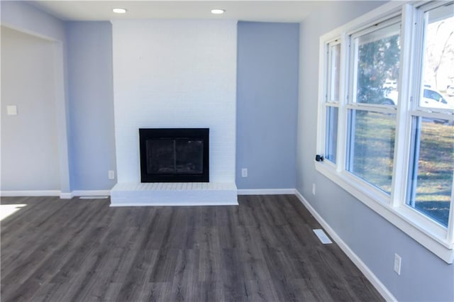 unfurnished living room with dark wood-type flooring and a brick fireplace