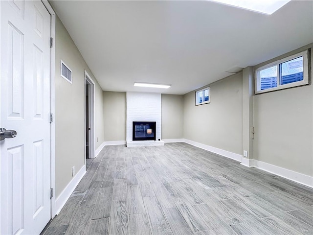 basement featuring a fireplace and light hardwood / wood-style flooring