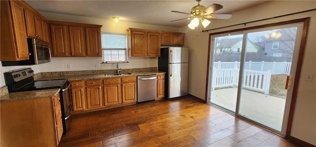 kitchen with stone counters, sink, ceiling fan, appliances with stainless steel finishes, and plenty of natural light