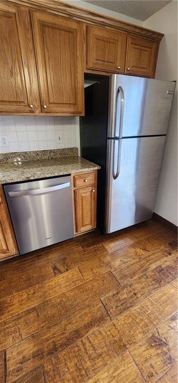 kitchen featuring stone counters, decorative backsplash, dark hardwood / wood-style flooring, and appliances with stainless steel finishes