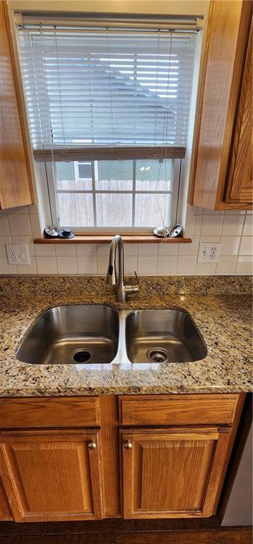 room details featuring decorative backsplash, sink, and light stone counters