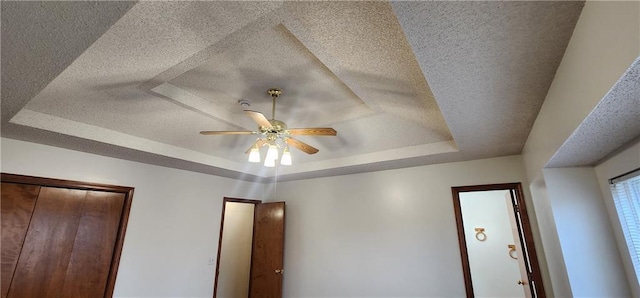 interior details with a tray ceiling and ceiling fan