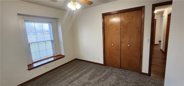 unfurnished bedroom with ceiling fan, a closet, and dark colored carpet