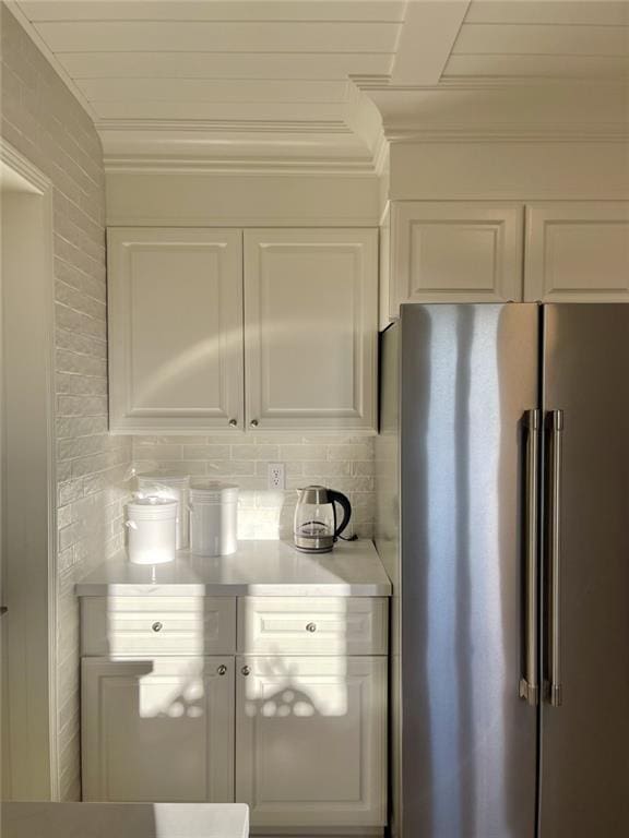 kitchen with decorative backsplash, white cabinetry, high end fridge, and ornamental molding