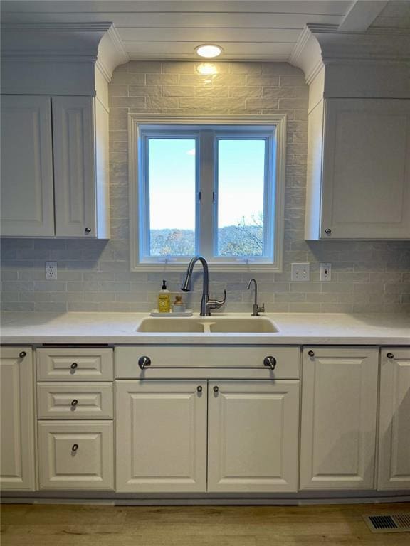 kitchen featuring white cabinets, sink, and tasteful backsplash