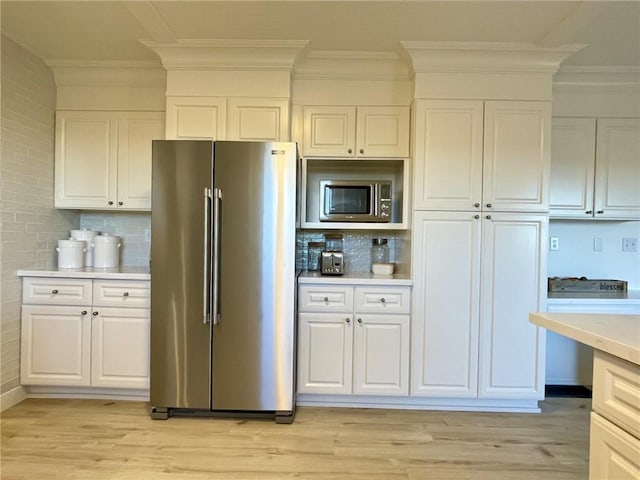 kitchen featuring decorative backsplash, light hardwood / wood-style flooring, white cabinets, and stainless steel appliances