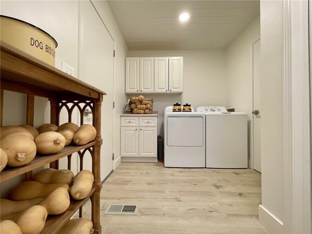 laundry room with cabinets, washing machine and clothes dryer, and light hardwood / wood-style flooring