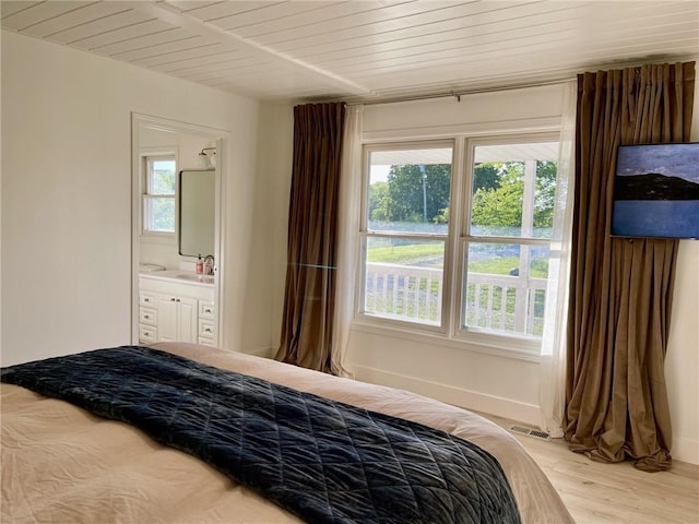 bedroom featuring ensuite bathroom, light wood-type flooring, sink, and multiple windows