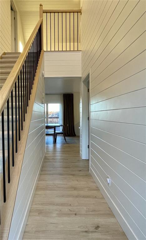 hallway featuring a towering ceiling and light wood-type flooring