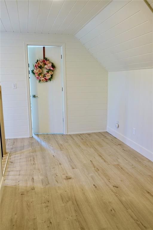 bonus room featuring light hardwood / wood-style floors, lofted ceiling, and wooden walls