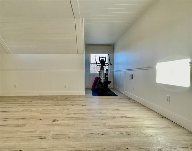 workout area featuring light wood-type flooring and vaulted ceiling