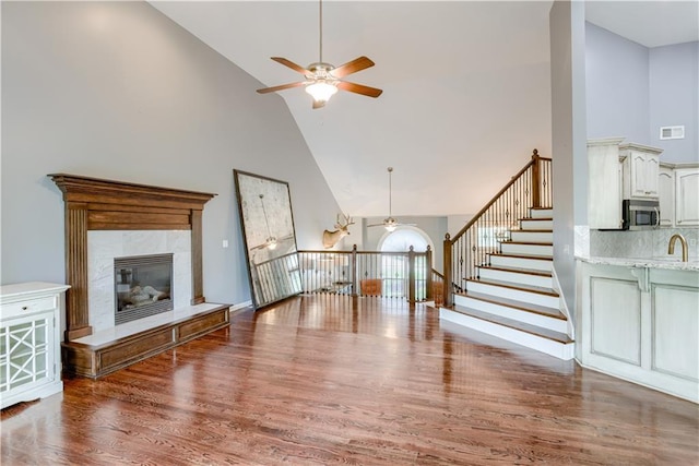 6764 Longview Rd, Shawnee, KS 66218 - unfurnished living room featuring ceiling fan, high vaulted ceiling, wood finished floors, a premium fireplace, and stairs