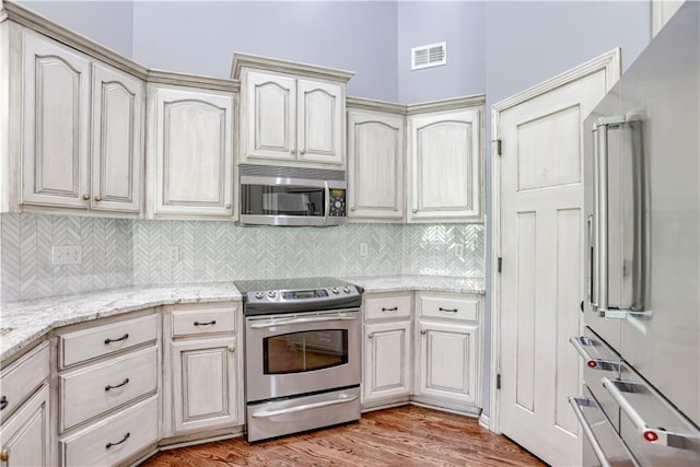6764 Longview Rd, Shawnee, KS 66218 - kitchen with appliances with stainless steel finishes, decorative backsplash, cream cabinetry, and light stone counters