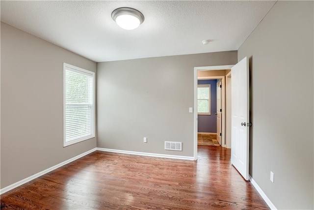6764 Longview Rd, Shawnee, KS 66218 - unfurnished room featuring healthy amount of natural light, wood finished floors, baseboards, and a textured ceiling