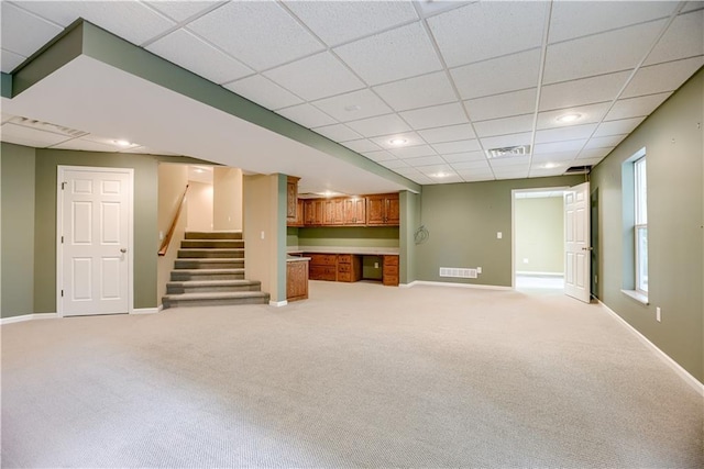 6764 Longview Rd, Shawnee, KS 66218 - unfurnished living room featuring a paneled ceiling, light colored carpet, baseboards, stairs, and built in desk