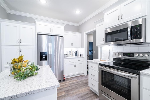 kitchen featuring decorative backsplash, stainless steel appliances, white cabinets, and crown molding