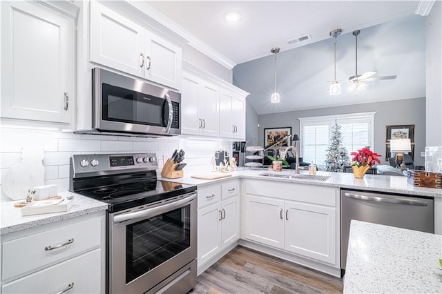 kitchen with white cabinets, sink, decorative backsplash, decorative light fixtures, and stainless steel appliances