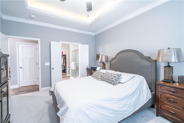 carpeted bedroom with a walk in closet, a closet, ceiling fan, and crown molding