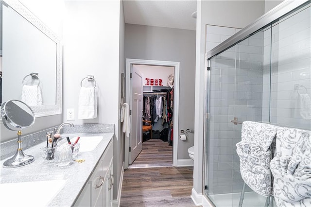 bathroom featuring vanity, wood-type flooring, an enclosed shower, and toilet