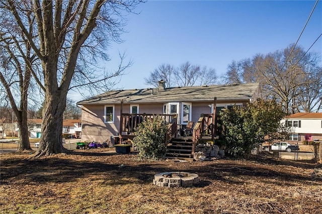 view of front of property with a fire pit, a deck, a chimney, and fence