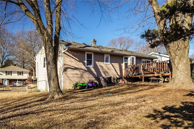 back of property with a chimney, fence, and a wooden deck